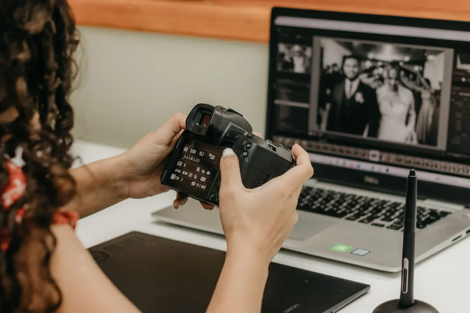 Photo by Kawê Rodrigues on Pexels A photographer checks camera settings in front of a laptop showing a black-and-white wedding photo.