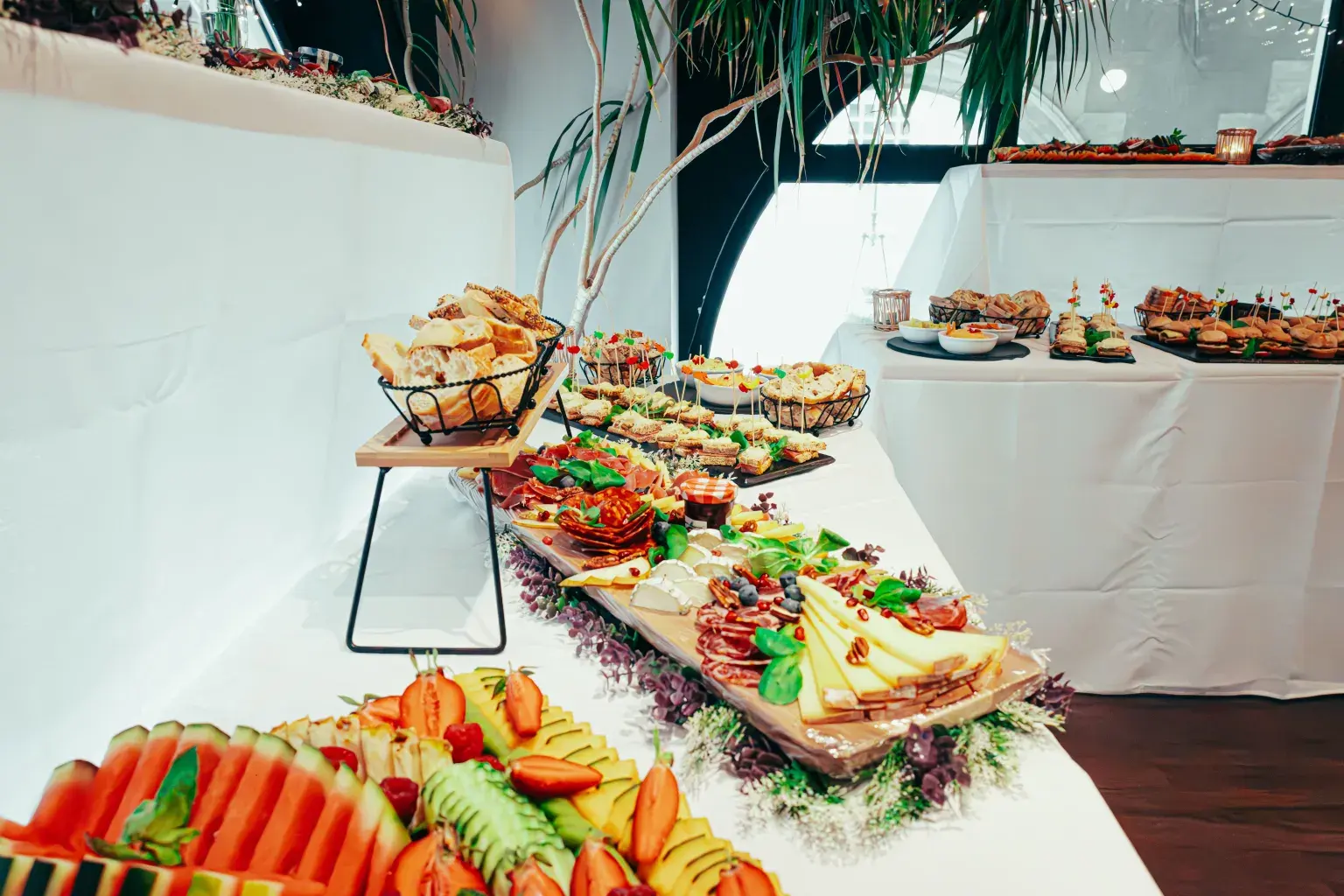Photo by Newman Photographs on Pexels A catered buffet of fruit, cheese, cured meats, and bread is set on white-draped tables at an event.