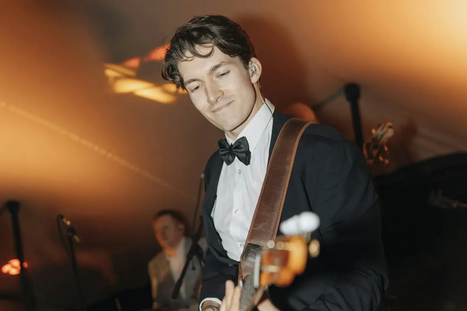 Photo by Ben Atkins on Unsplash A tuxedoed guitarist performs with a drummer behind him.