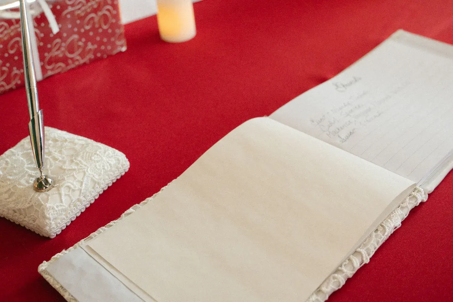 Photo by Taylor Thompson on Pexels An open wedding guest book and pen sit on a red tablecloth.