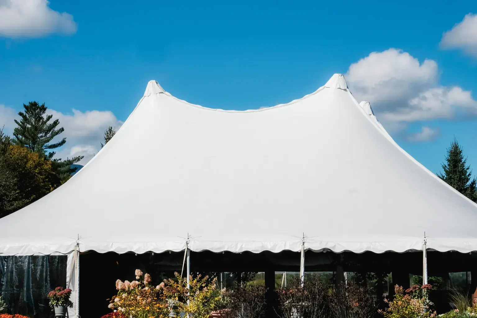 Photo by Sydney Sang on Pexels A large white event tent stands outdoors under a blue sky.