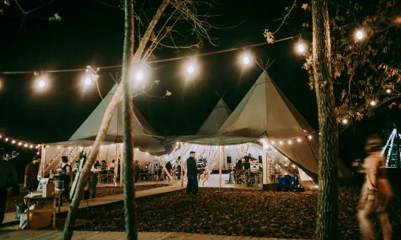 Nordic tipis and reception tables under string lights at night
