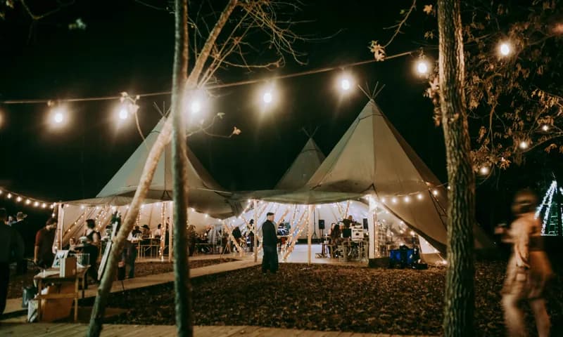 Nordic tipis and reception tables under string lights at night