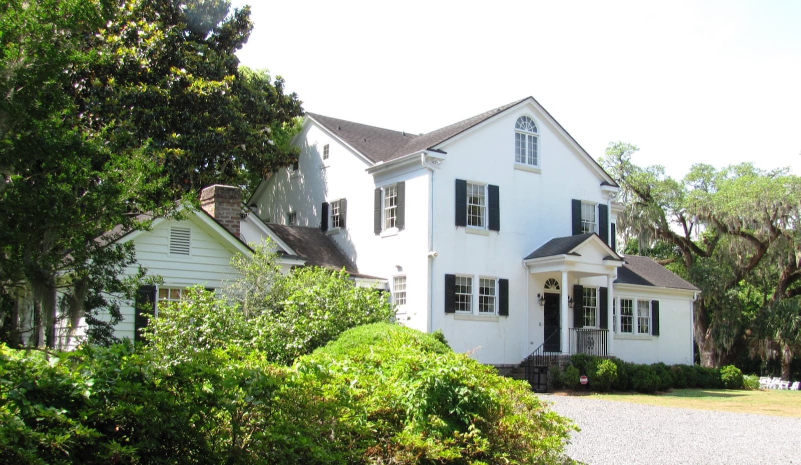 White exterior of the Legare Waring House at Charles Towne Landing, framed by trees
