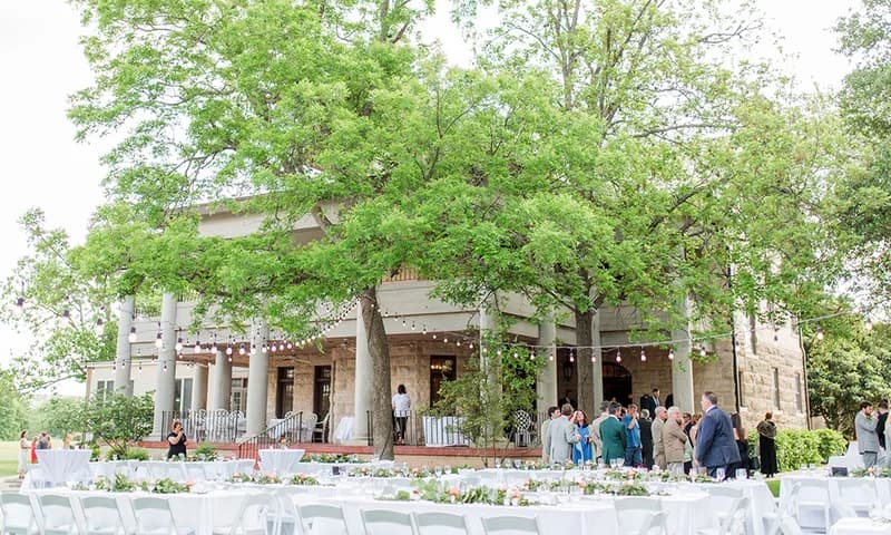 Outdoor reception tables beside the stone mansion
