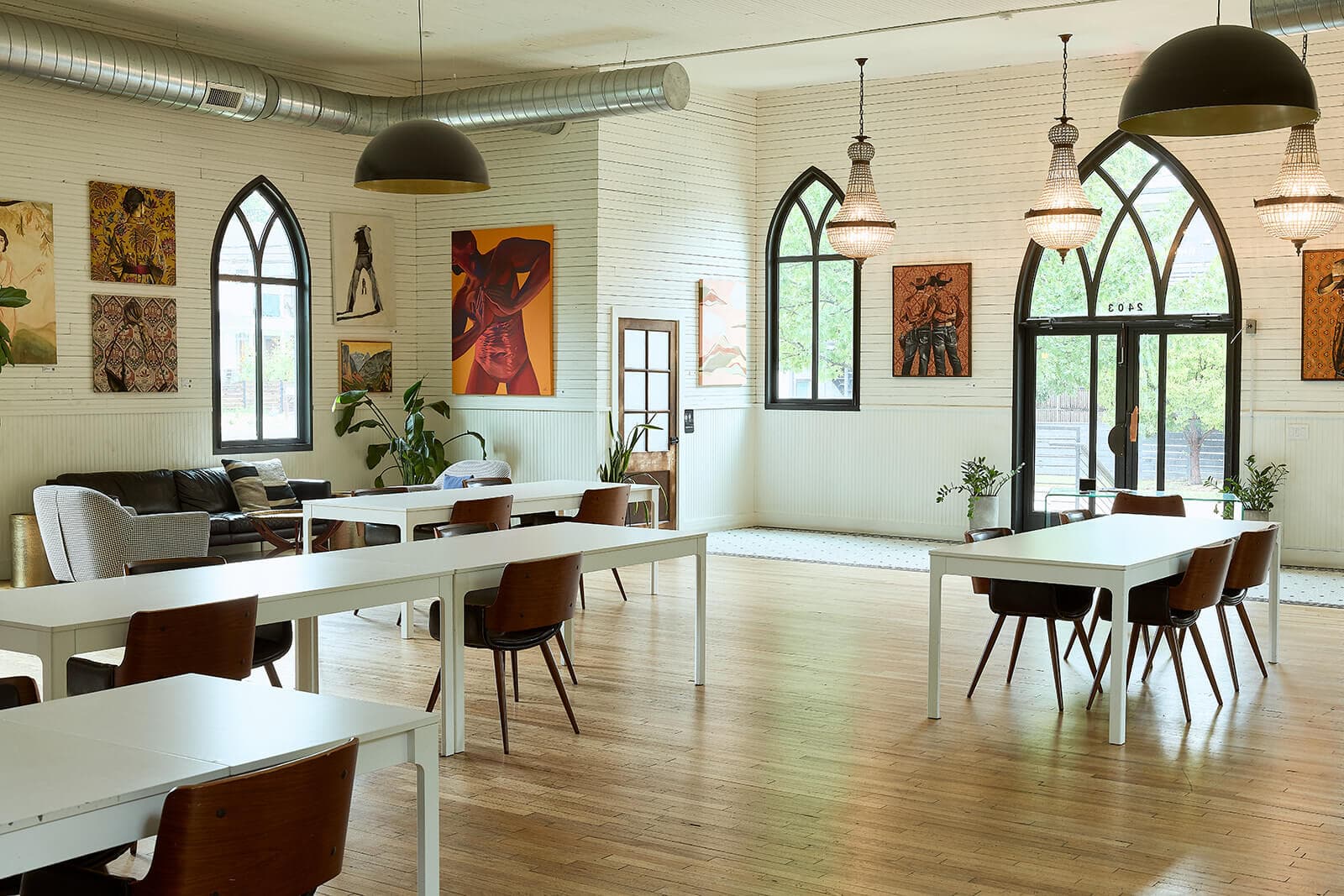 White church interior with arched windows, wood floors, chandeliers, and local art