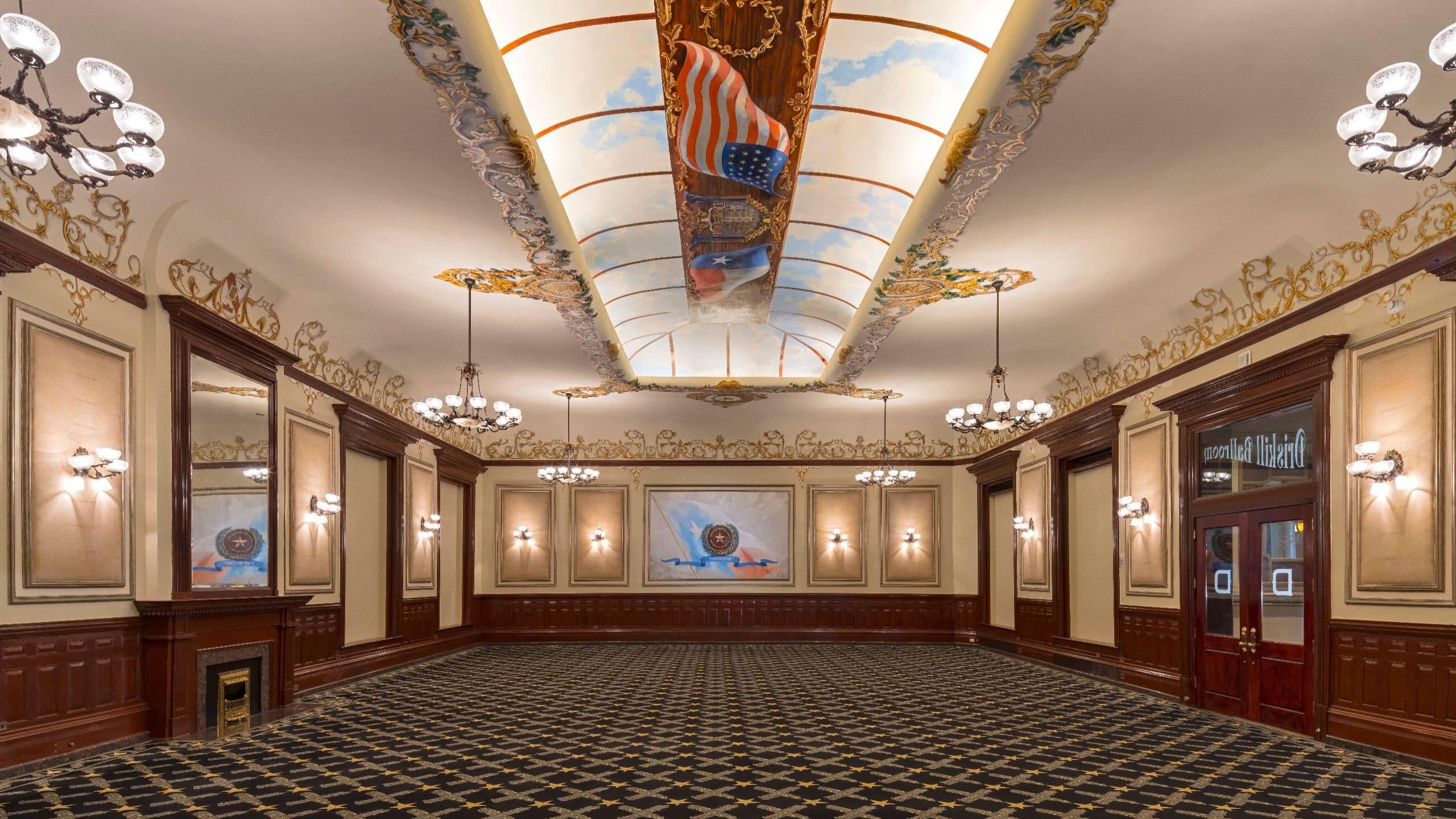 Historic Driskill Ballroom with ornate ceiling murals, chandeliers, and dark wood trim