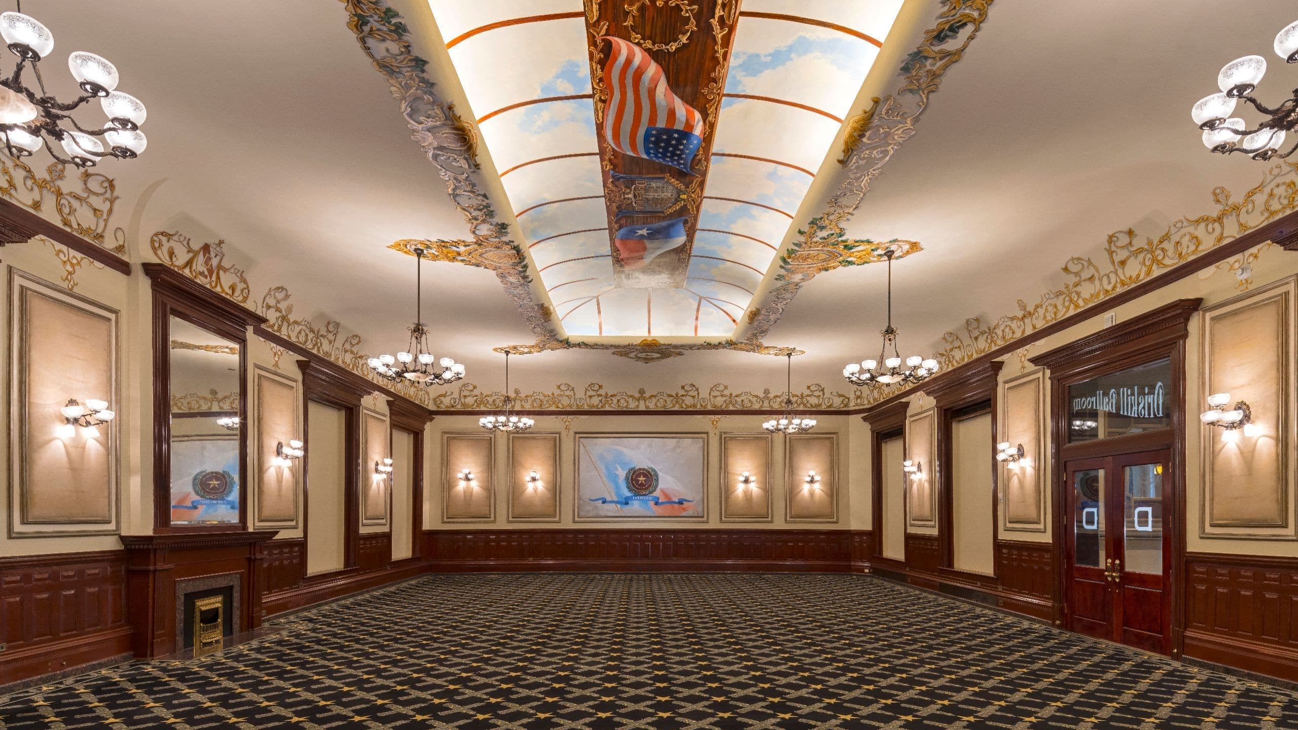 Historic Driskill Ballroom with ornate ceiling murals, chandeliers, and dark wood trim