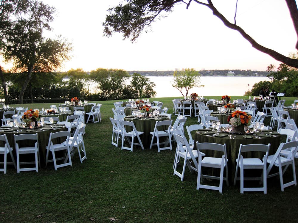 Reception tables on a lawn overlooking White Rock Lake at the Dallas Arboretum