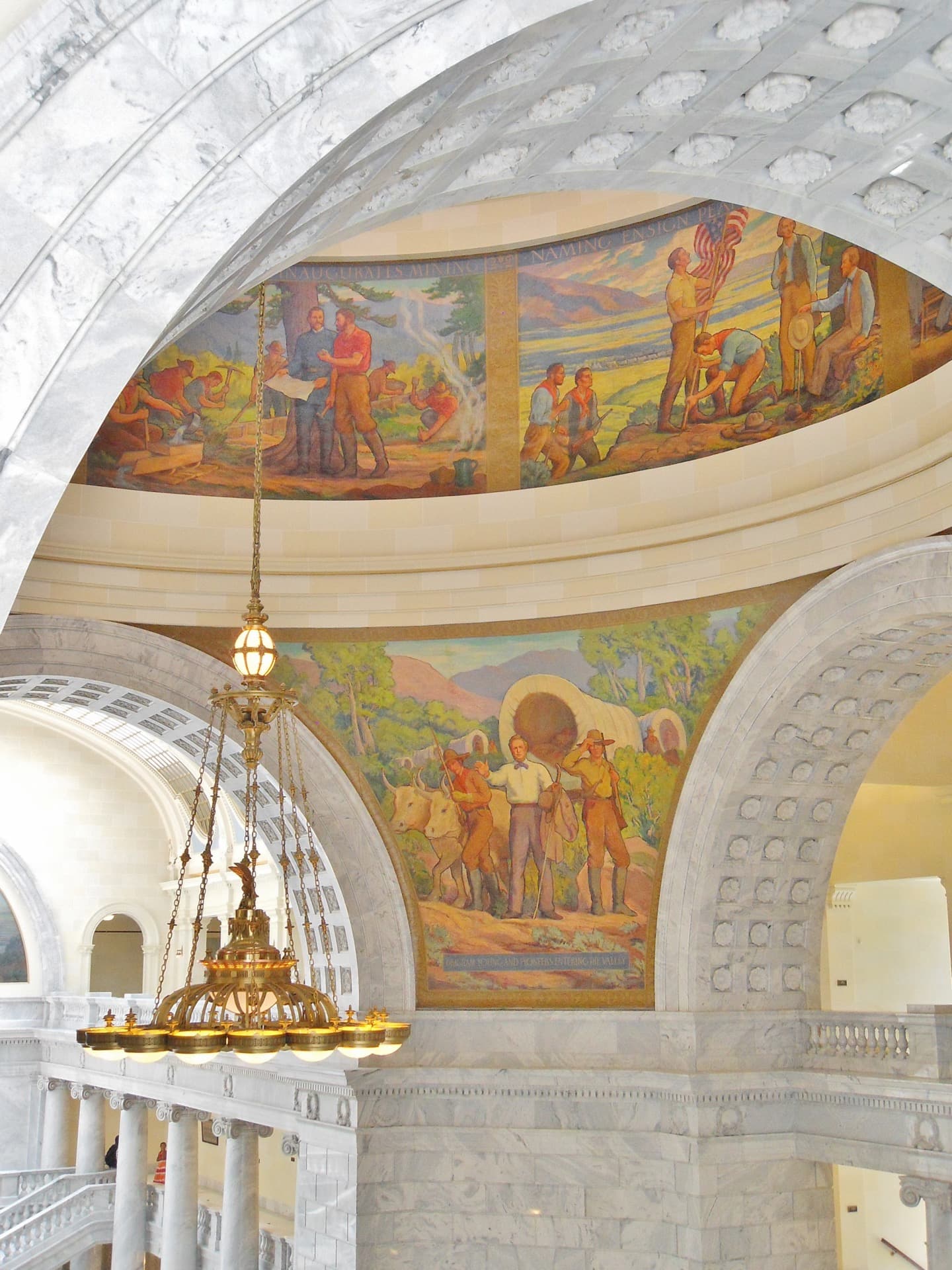 Historic mural, marble arches, and chandelier inside the Utah State Capitol Rotunda